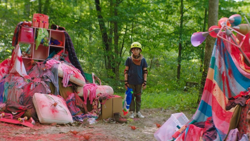 Jack (Kue Lawrence) stands among paint-splattered pillow forts in the woods in the movie Sketch. Image courtesy of Angel Studios.