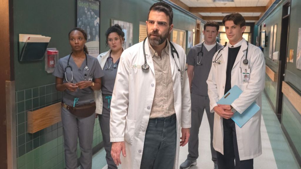 Zachary Quinto as Dr. Oliver Wolf standing in a hallway with his staff in the Brilliant Minds season 2 premiere. (Photo Credit: Courtesy of NBC.)